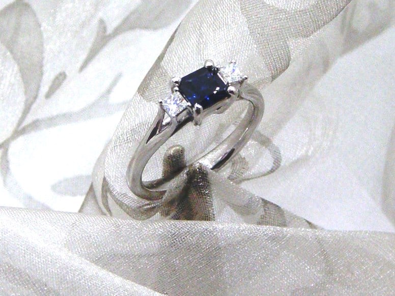 Stylish Sapphire Diamond Ring set with square cut sapphire & princess cut diamonds with sweep shoulder detail.  Beth Blue was custom made in 18ct white gold ~ Sapphire Weight - 0.70 carat ~ Diamond Weight- 0.15 carat.   Sapphire is a pretty mid/dark blue with light colour flashes ~ CAD renders show detail of design.     
