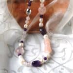 Freshwater Pearl Necklace designed with pebble shaped Amethyst, Rose Quartz in an asymmetrical pattern and featuring a carved Rose Quartz cylinder. The Necklace is finished with an Oval shape Sterling Silver Clasp.