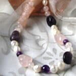 Freshwater Pearl Necklace designed with pebble shaped Amethyst, Rose Quartz in an asymmetrical pattern and featuring a carved Rose Quartz cylinder. The Necklace is finished with an Oval shape Sterling Silver Clasp.