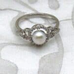 Delicate Pearl Diamond Ring set with Cultured Freshwater Pearl with Halo & Circle Shoulders pave set with Accent Diamonds. Designed in 18ct White Gold - Freshwater Pearl measures 7mm - Diamond Weight 0.20 carat - Unique Pearl Diamond Ring White Gold.